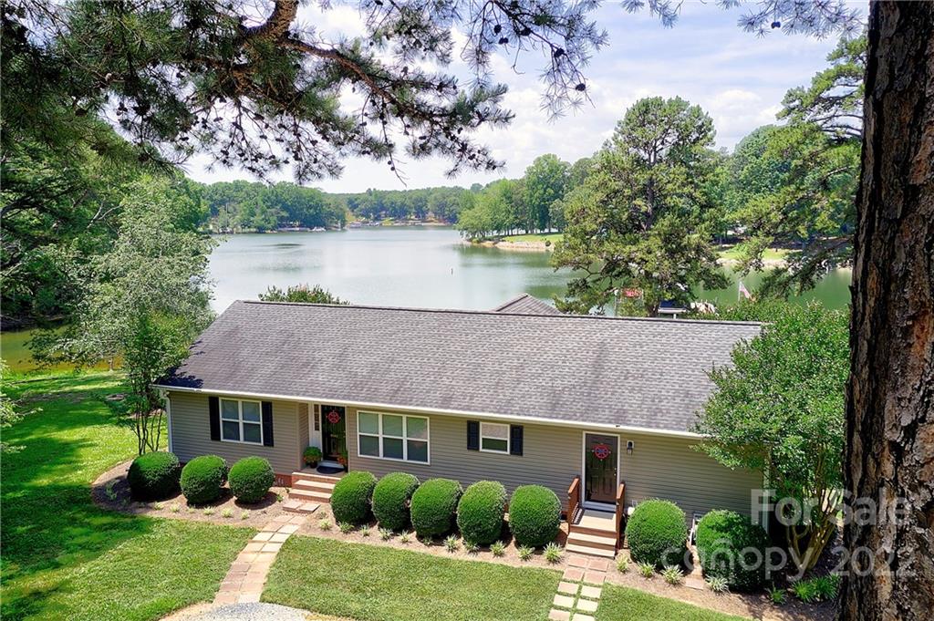 Lakeside house with lush greenery and lake view.