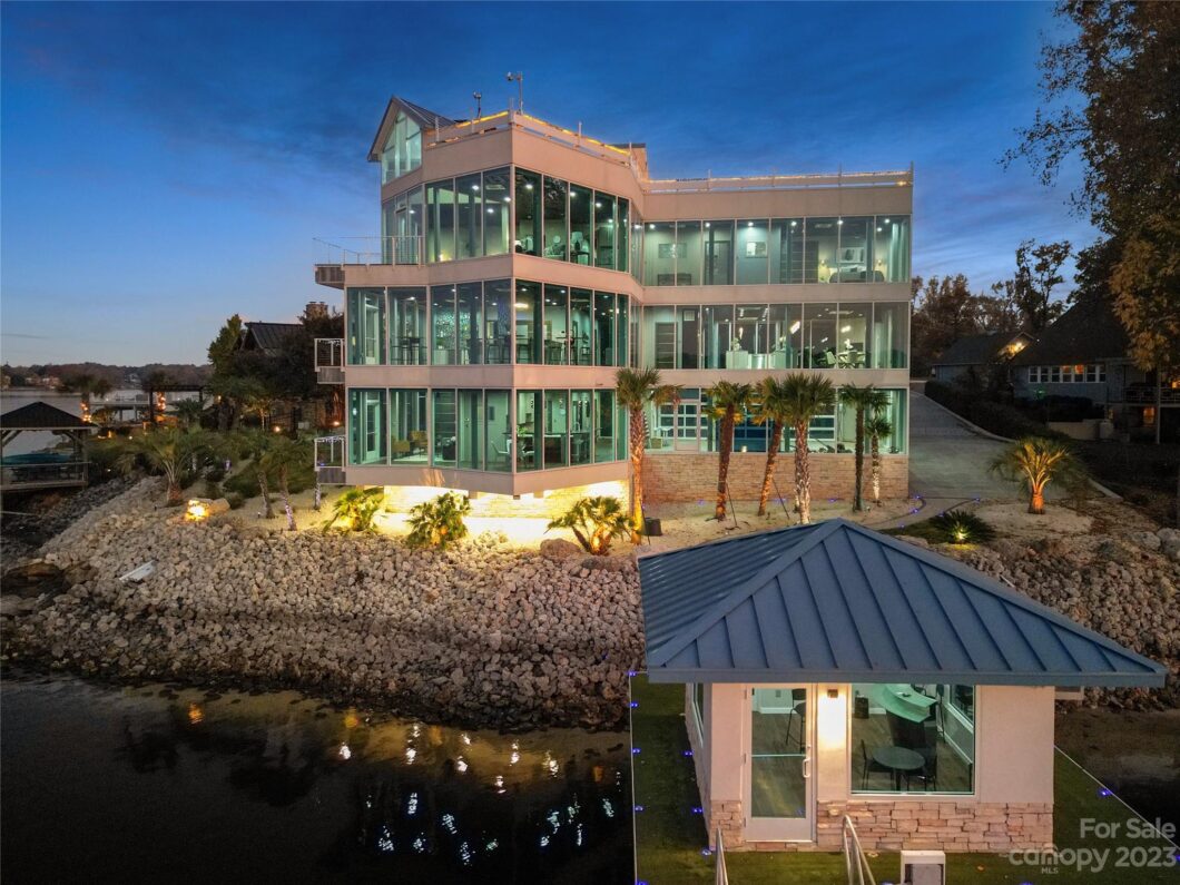 Modern glass building by a lakeshore at dusk.