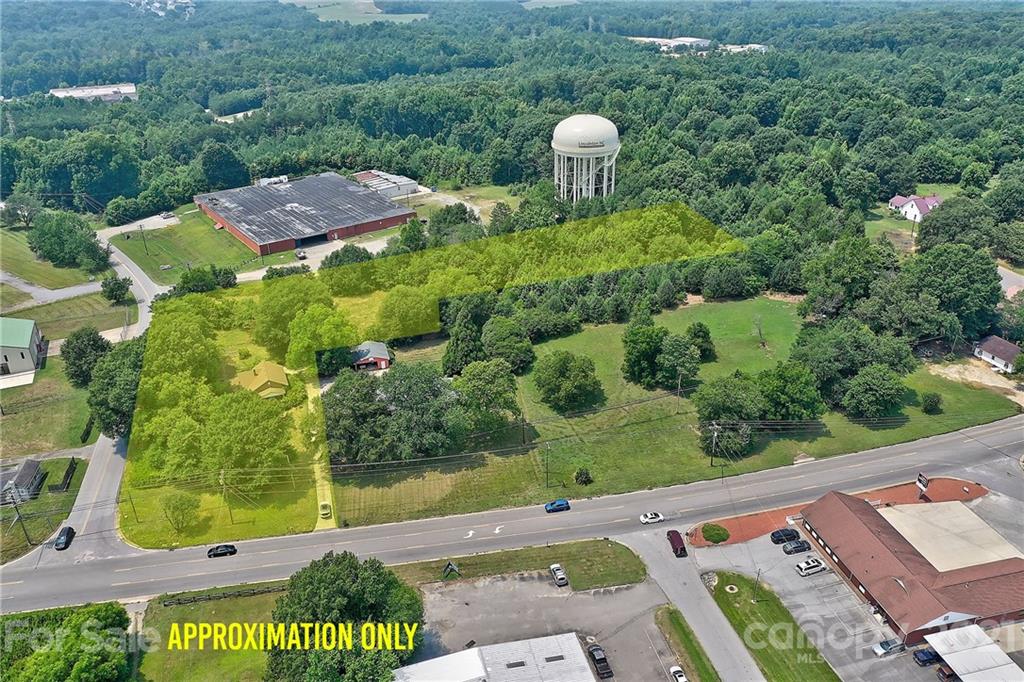 Aerial view of highlighted property for sale, forest backdrop.