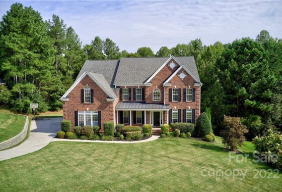 Two-story brick house with manicured lawn and trees.