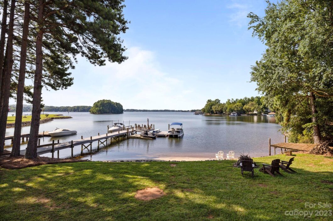Lakeside view with dock and boats under blue sky.