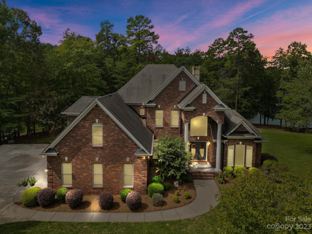 Brick house for sale at sunset with landscaped yard.